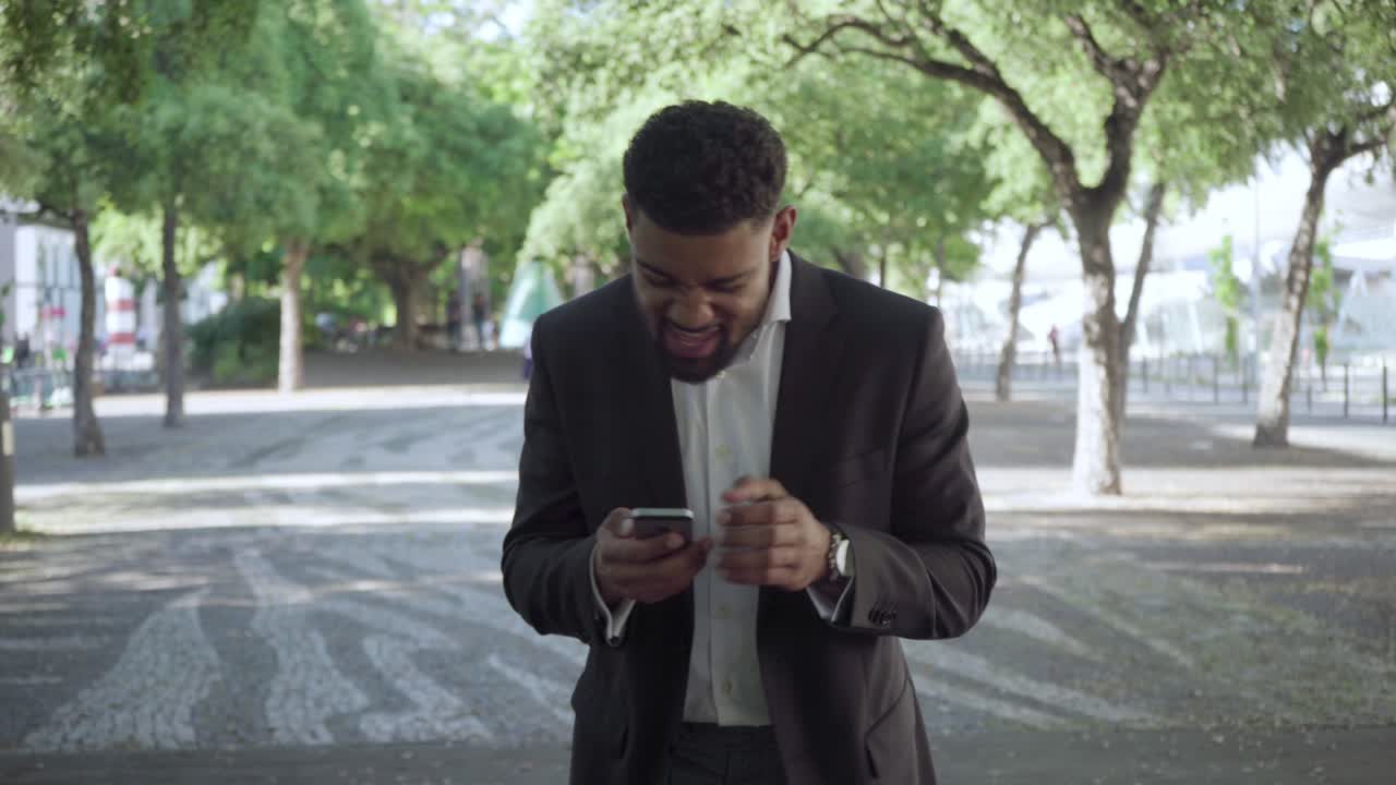 Smiling young man reading good news from smartphone