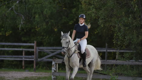 Professional-girl-rider-galloping-on-a-horse.-Girl-riding-a-horse-on-an-arena-at-sunset.-Horse-hoof-creates-a-lot-of-dust.-Competitive-rider-training-jumping.