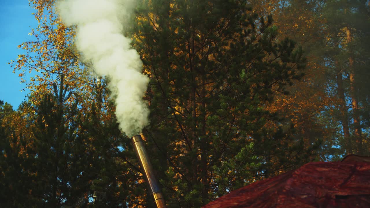 La canna fumaria di una stufa a legna di un campo nella foresta boreale fuma in un campeggio autunnale