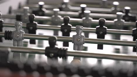 focused detail shot of a silver character of a table soccer game representing a man in a row of a team or symbolic surrounded in the crowd - isolation