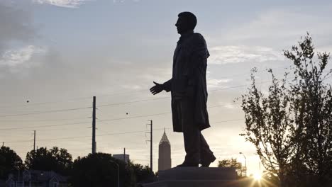 wide shot of statue looking over park as the sunrises in the background