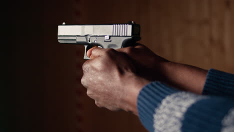 hombre con una pistola en el campo de tiro interior, de cerca