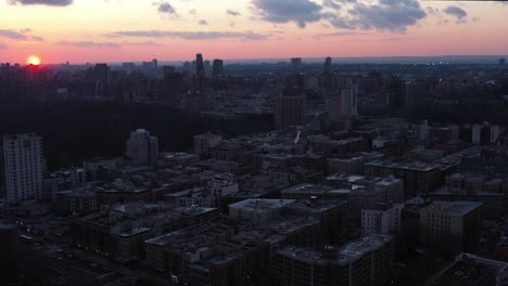 aerial flight over new york city's harlem neighborhood with gorgeous setting sun and clouds visible.