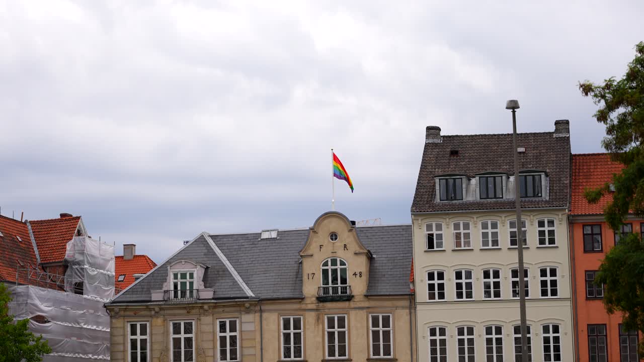 foto de mano de una bandera lgbttqi + ondeando en la parte superior de un viejo edificio en copenhague