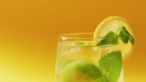 close up of drink with lemon on yellow background