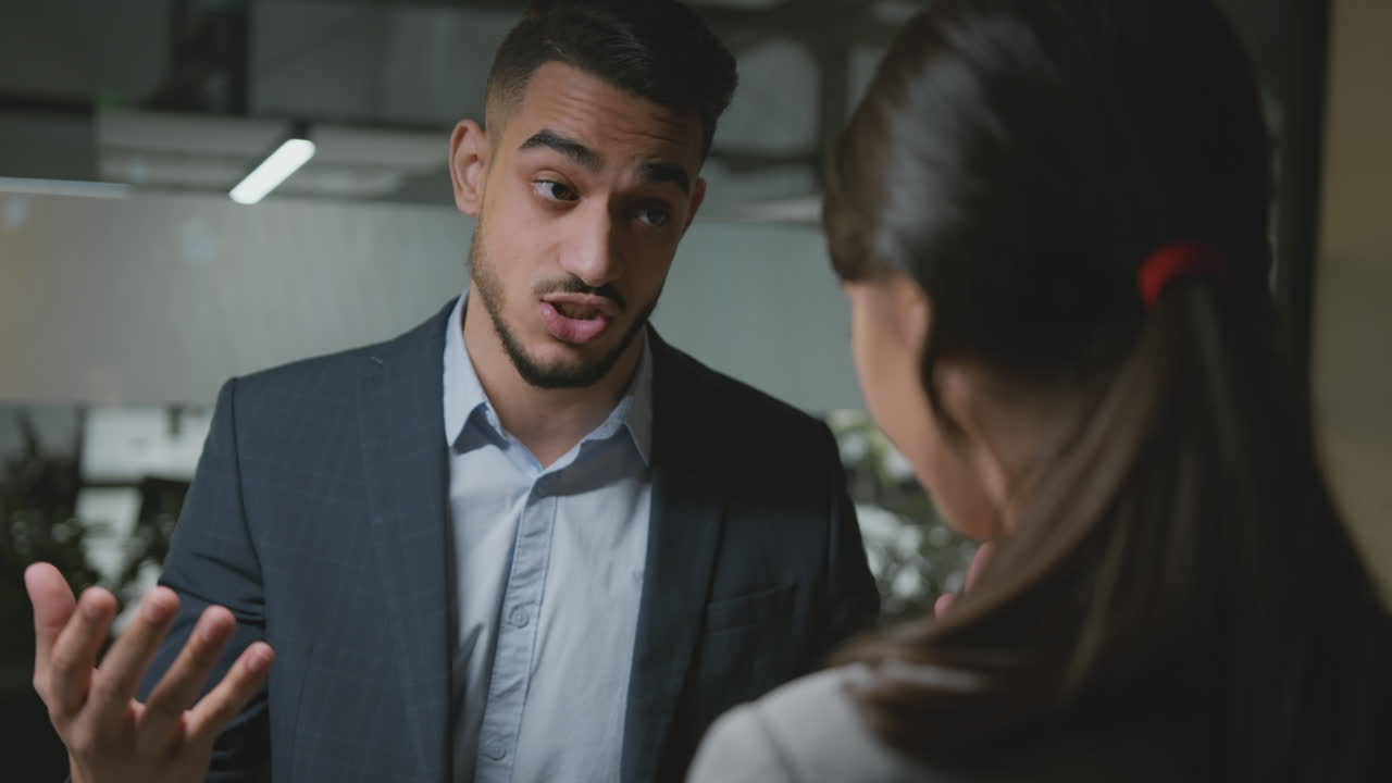 Man Gesturing While Talking to a Woman in an Office Setting