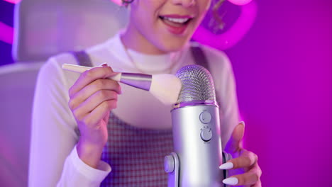 woman with makeup brush touching microphone