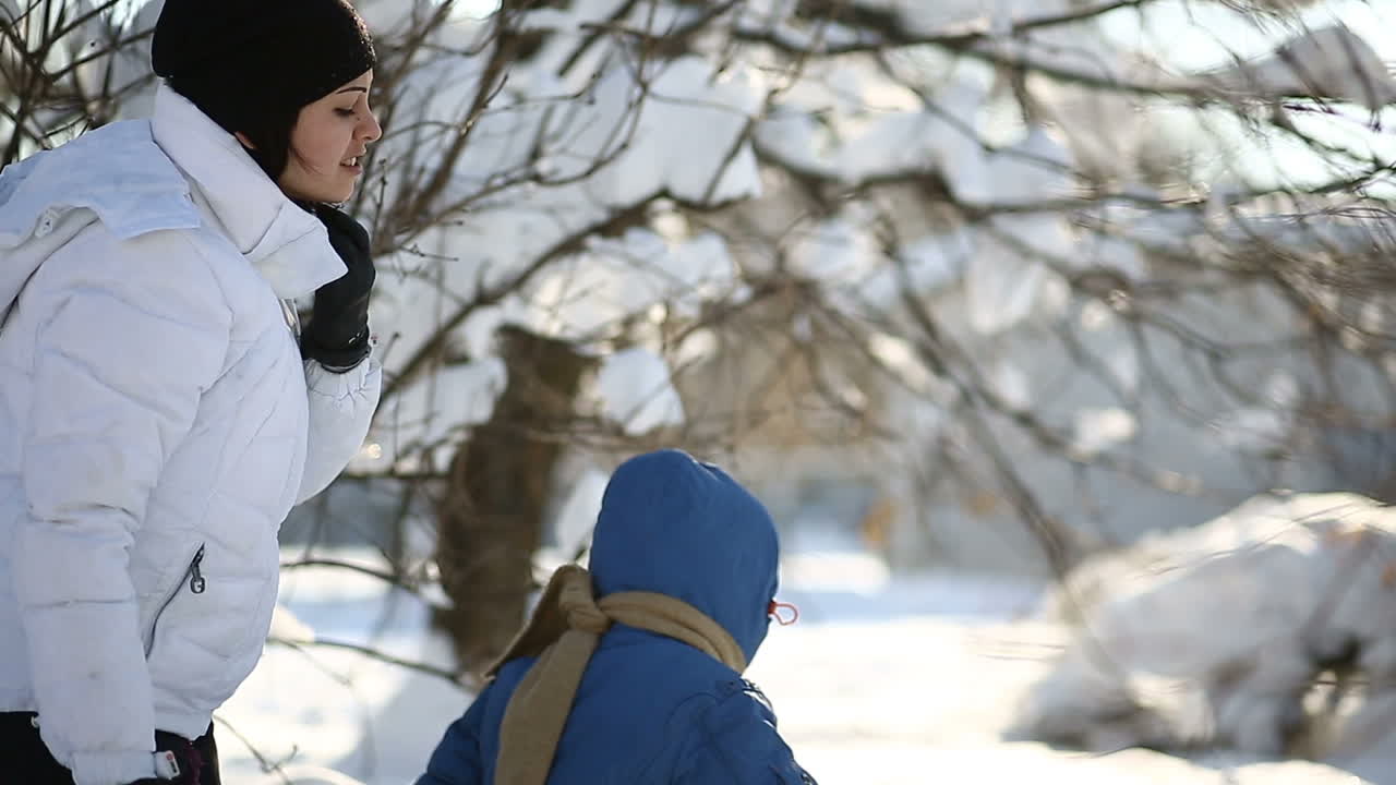 Mother walking with son. Small child and mother in the winter outside in warm clothes