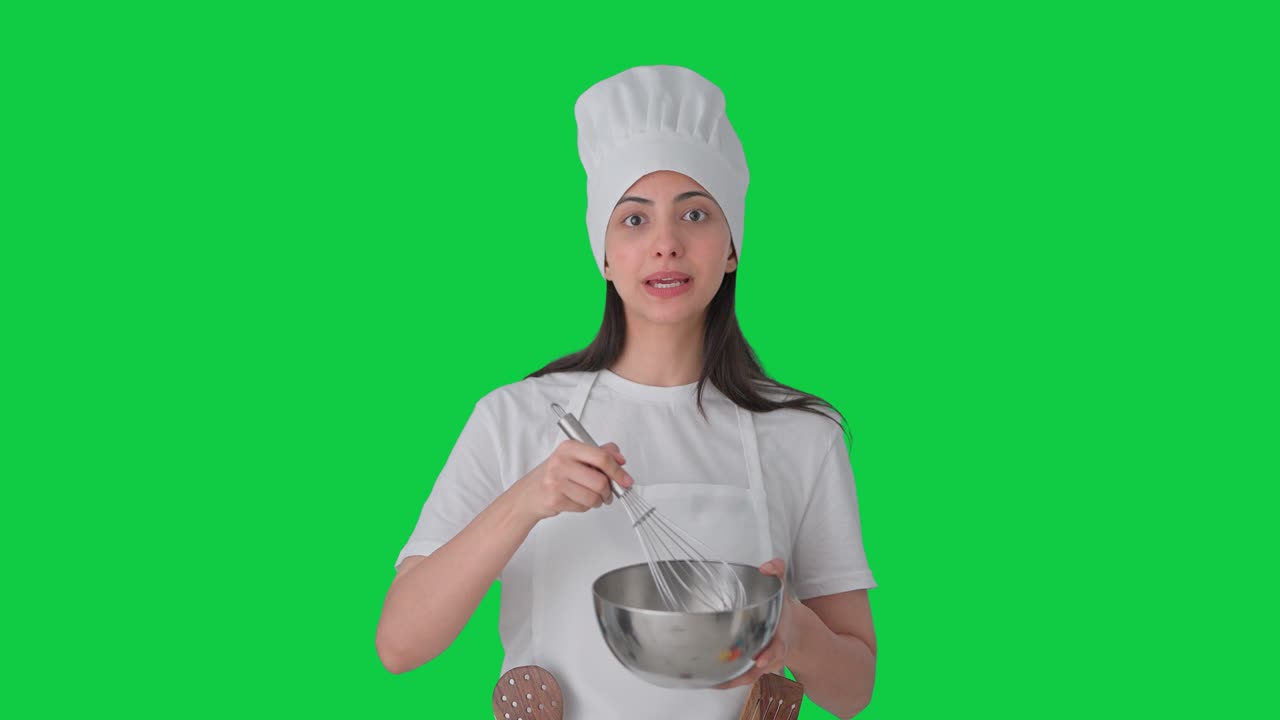 Chef professionista indiana che prepara il cibo mentre spiega, su green screen
