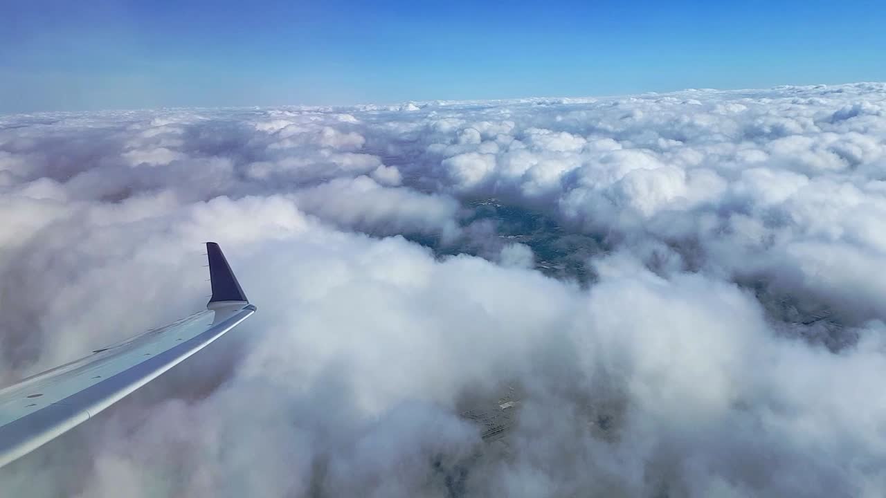 Airplane flying above the clouds and banking left tipping the wing down