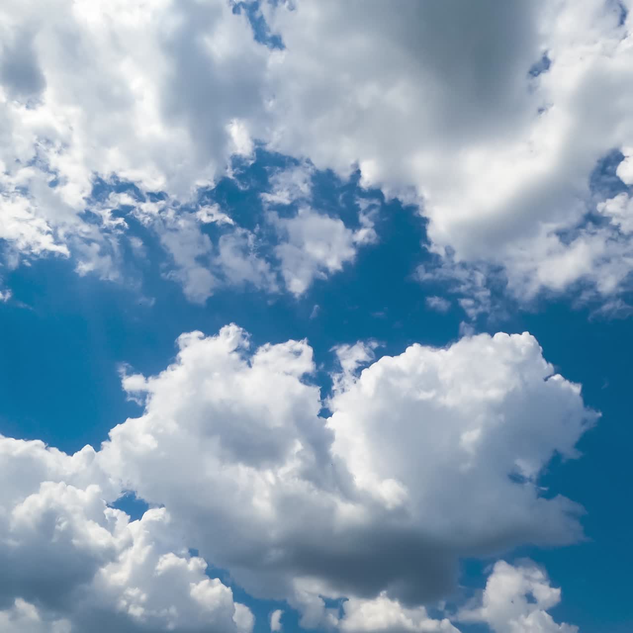 Multiple cotton clouds quickly transforming in the atmosphere. Soft cloudscape formation on sunny daytime. Timelapse