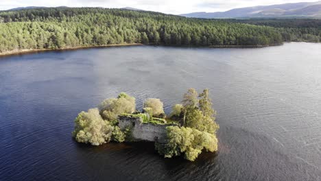 aerial view of ruins of loch an eilein castle in lake surrounded by rothiemurchus forest