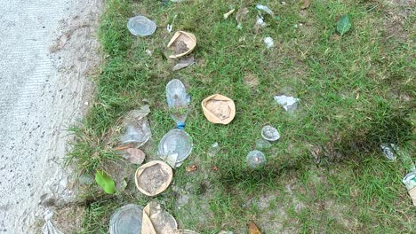 plastic and organic waste scattered on grassy roadside in koh samui, thailand. daylight highlights environmental pollution