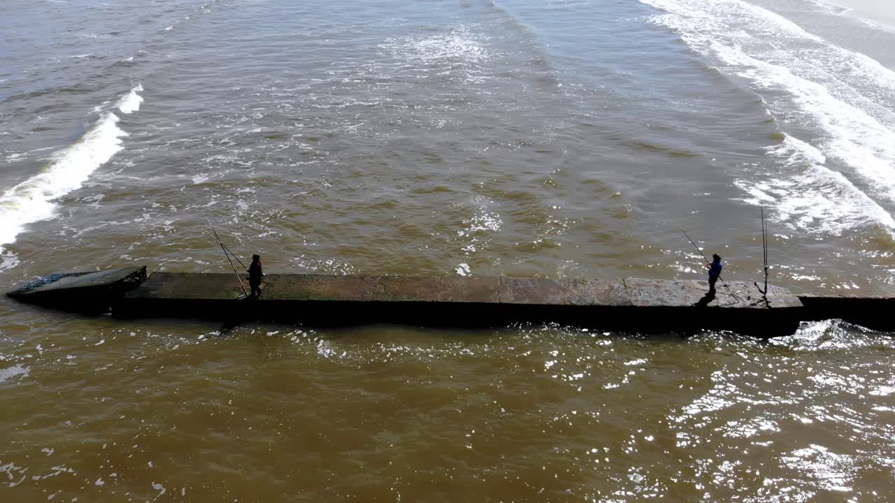 해변에서 낚시하는 두 사람의 항공 영상, 파도가 있는 어느 날