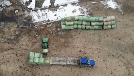 from field to barn: an aerial shot of tractor unloading and stacking hay bales on a farm in british columbia, canada