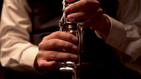 reproductor de dedos en el clarinete, en una habitación oscura