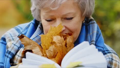 senior woman reading in autumn park