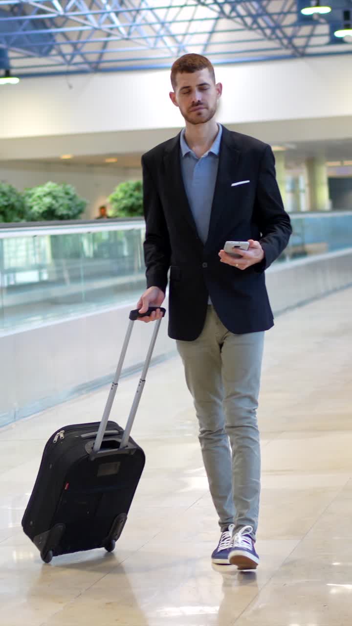 Man traveling in airport with luggage and smartphone