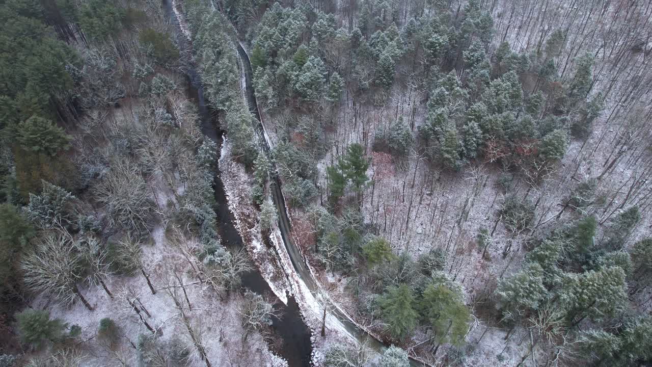 кадры с беспилотного летательного аппарата, снятые на красивой дороге через заснеженный зимний лес в горах аппалачи зимой в долине гудзон в нью-йорке в субрегионе гор катскилл