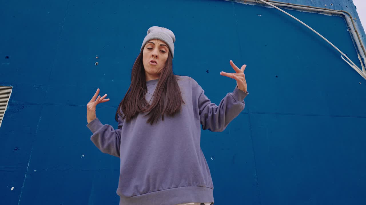 Woman in gray outfit in front of a blue wall