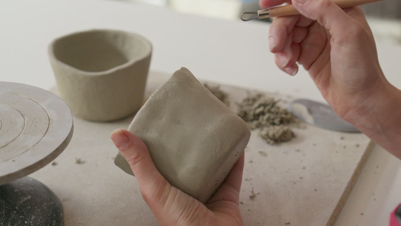 Picking up tools to masterfully engrave intricate designs into soft clay showcasing artisan's delicate touch