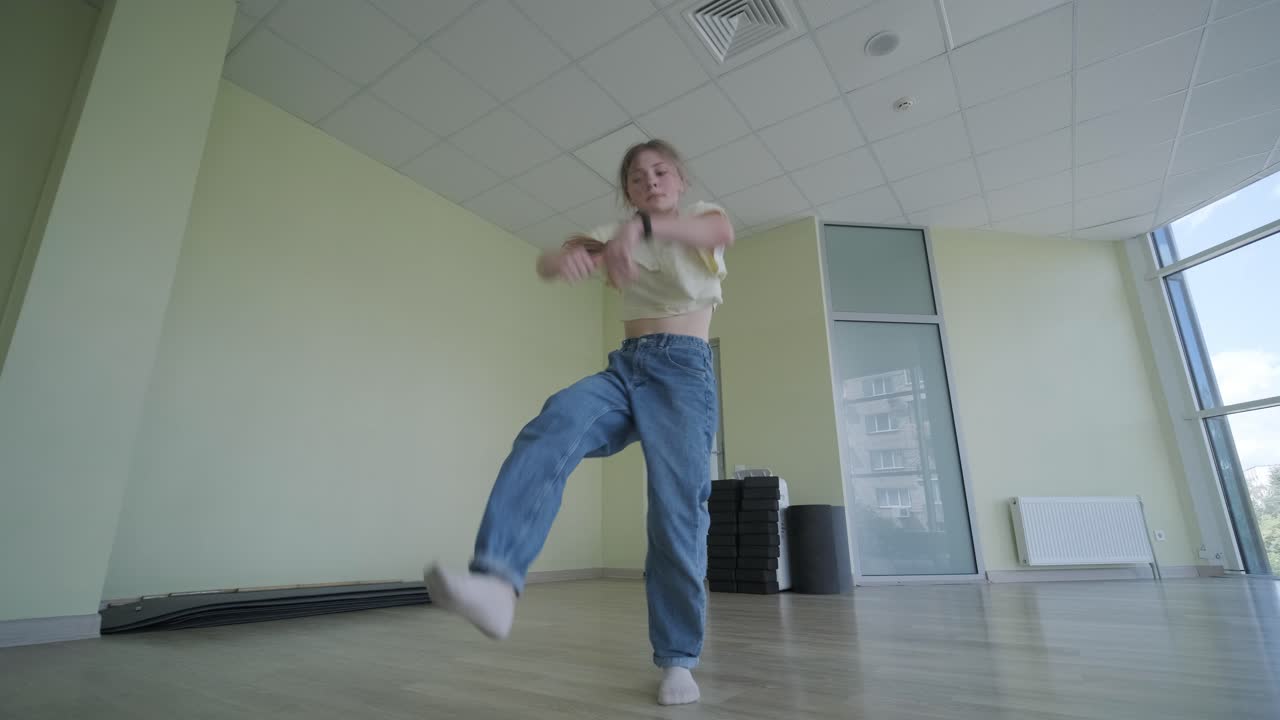 una chica joven bailando breakdance en un estudio moderno.