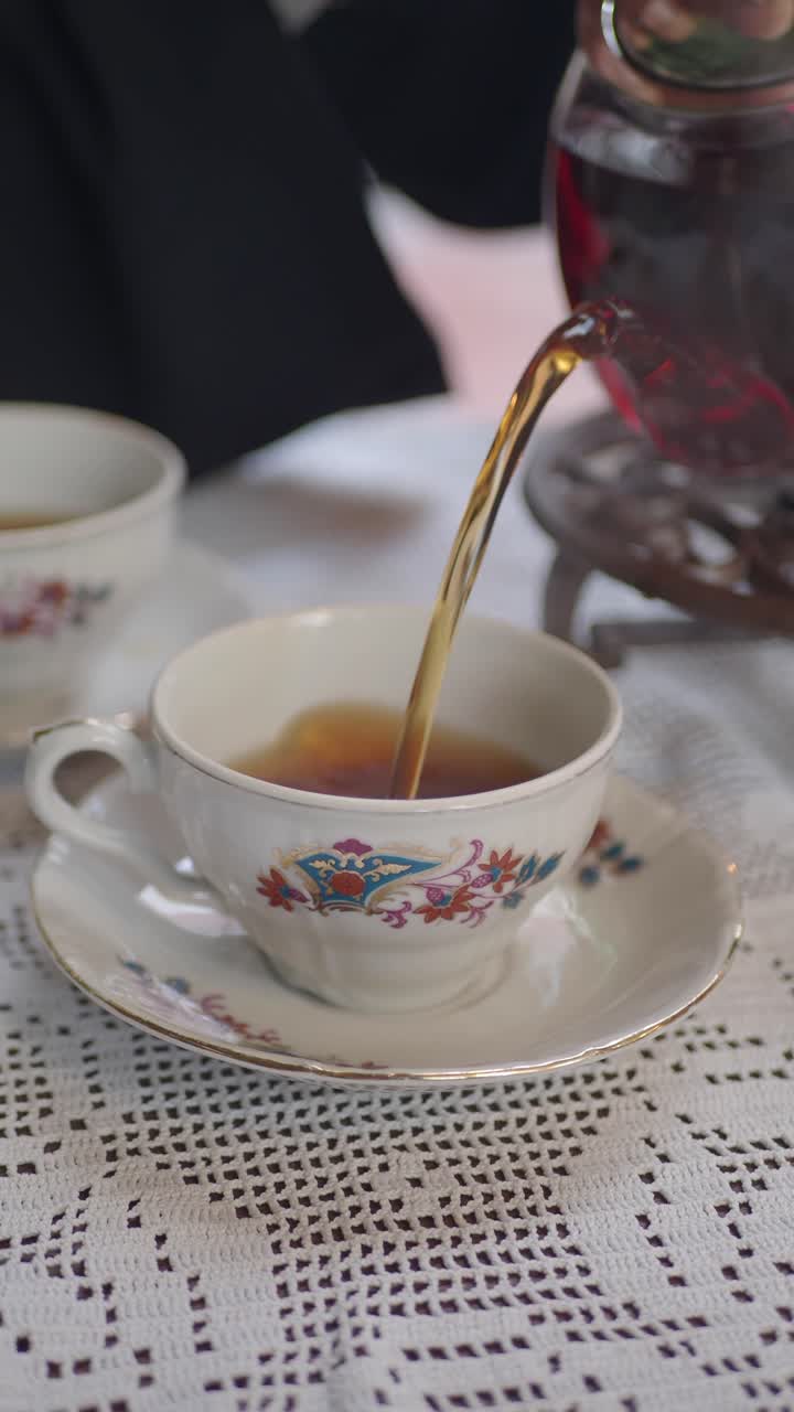 Versamento di tè caldo in una tazza da tè vintage su una tovaglia di pizzo