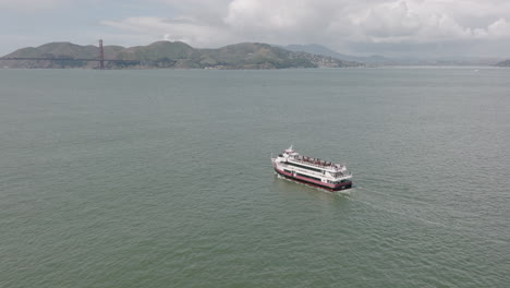 aerial rotating shot of ferry with golden gate bridge in background in san francisco, ca