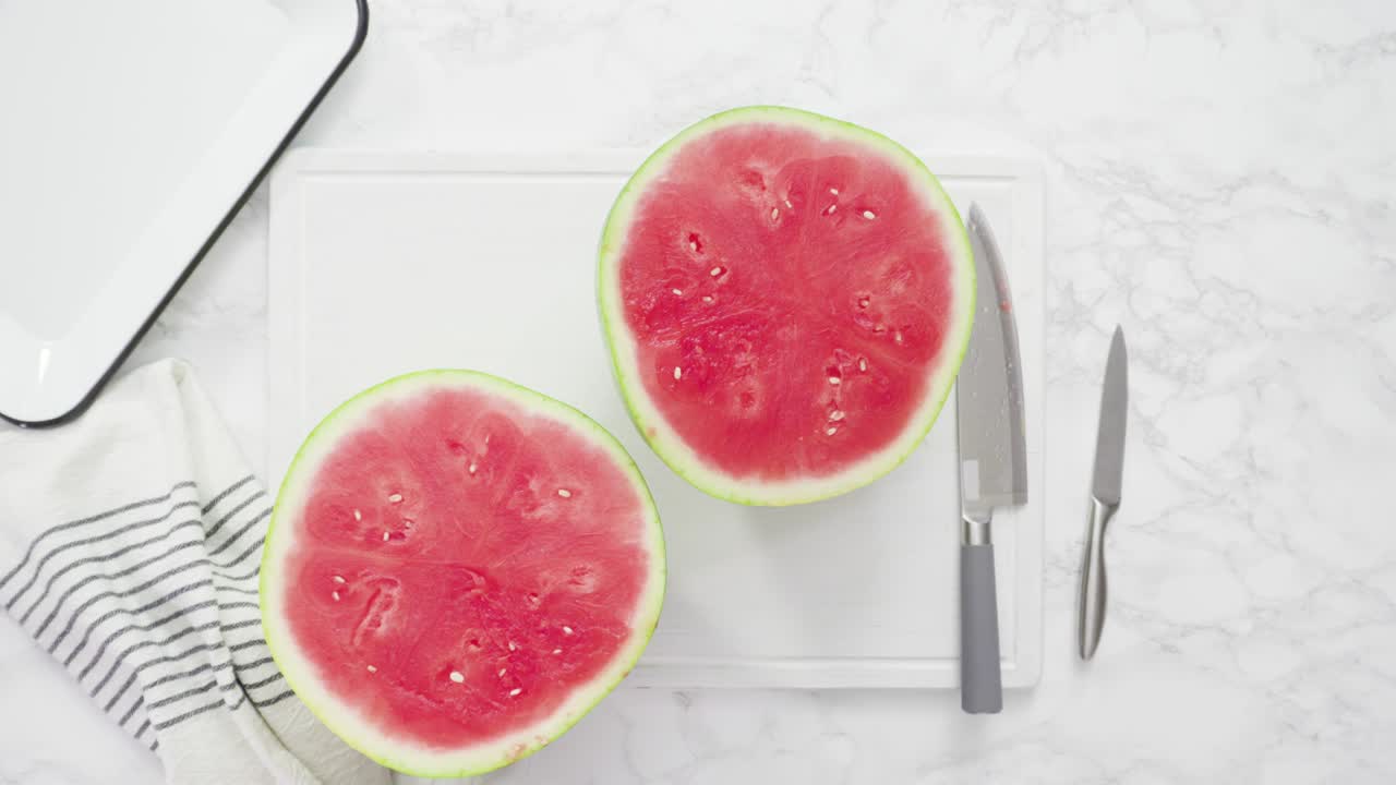cortar la sandía roja en pedazos pequeños en una tabla de cortar blanca.