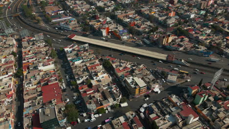 Vista-Aérea-Del-área-Suburbana-Mexicana-Con-Intersección-De-Carreteras-Con-Tráfico-De-Automóviles-En-Movimiento