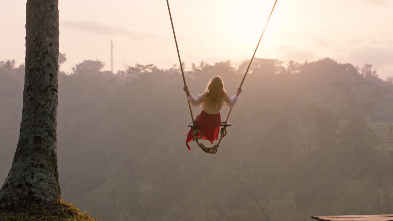 viajera mujer balanceándose sobre la selva tropical al amanecer turista mujer sentada en un columpio con una vista panorámica disfrutando de la libertad de vacaciones divirtiéndose estilo de vida de vacaciones cámara lenta