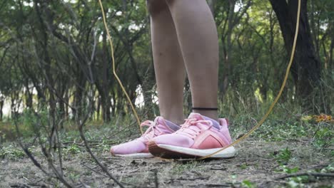 hermosa mujer atlética ejercicios con salto, saltando la cuerda en el bosque