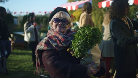senior woman in sunglasses stand with bag senior woman in sunglasses stand with bag of vegetables posing and looks at camera spending leisure time outdoor weekend on farmers market