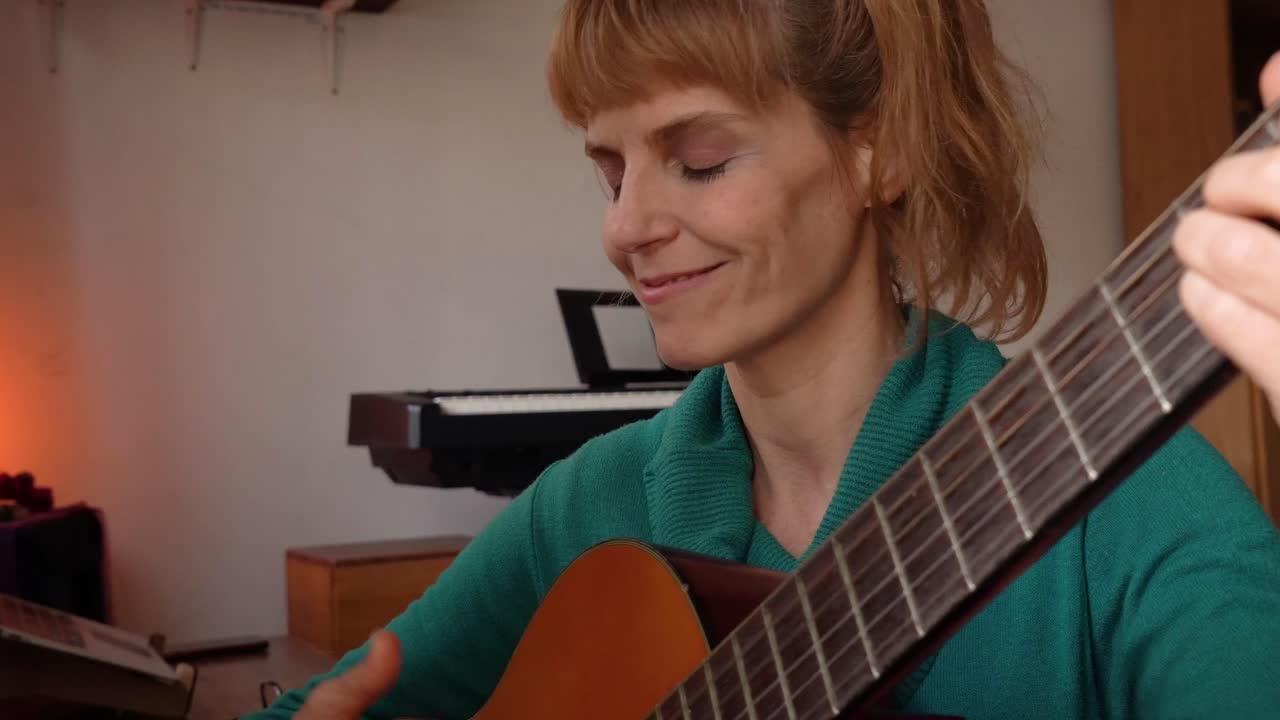 Mulher latina inspirada com violão cantando uma música em casa