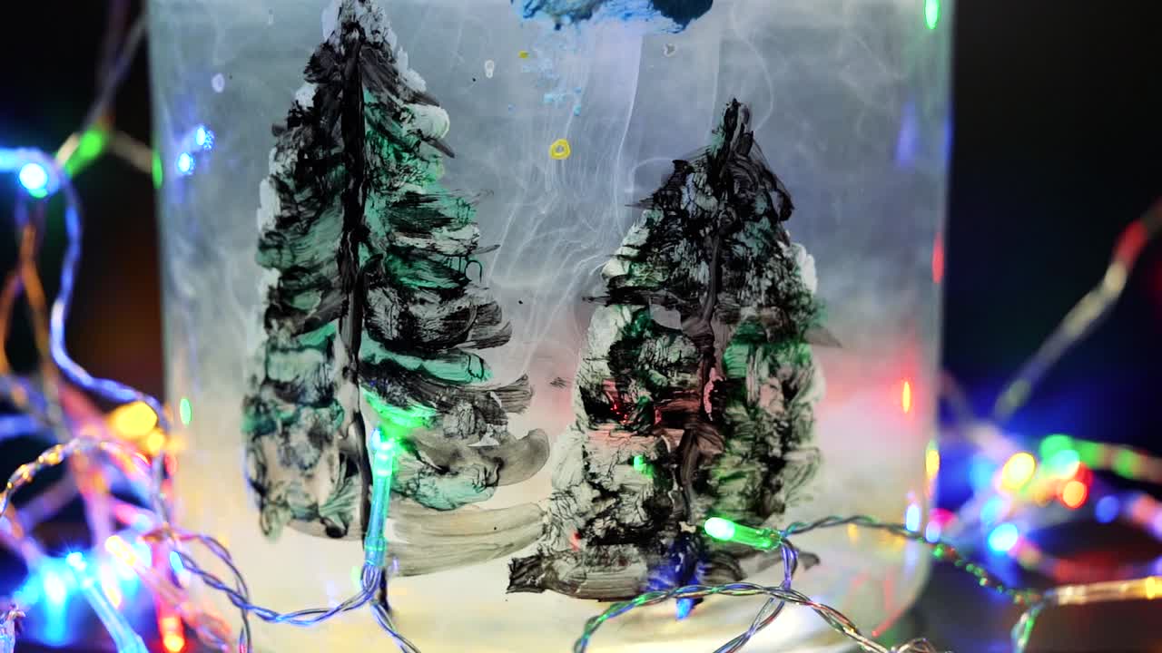 Paint floating in water tank with pine trees drawing inside. Stable shot with the Sony a7iii.