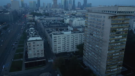 Forwards-fly-above-urban-neighbourhood-before-sunrise.-Tilt-up-reveal-cityscape-with-modern-high-rise-buildings.-Warsaw,-Poland