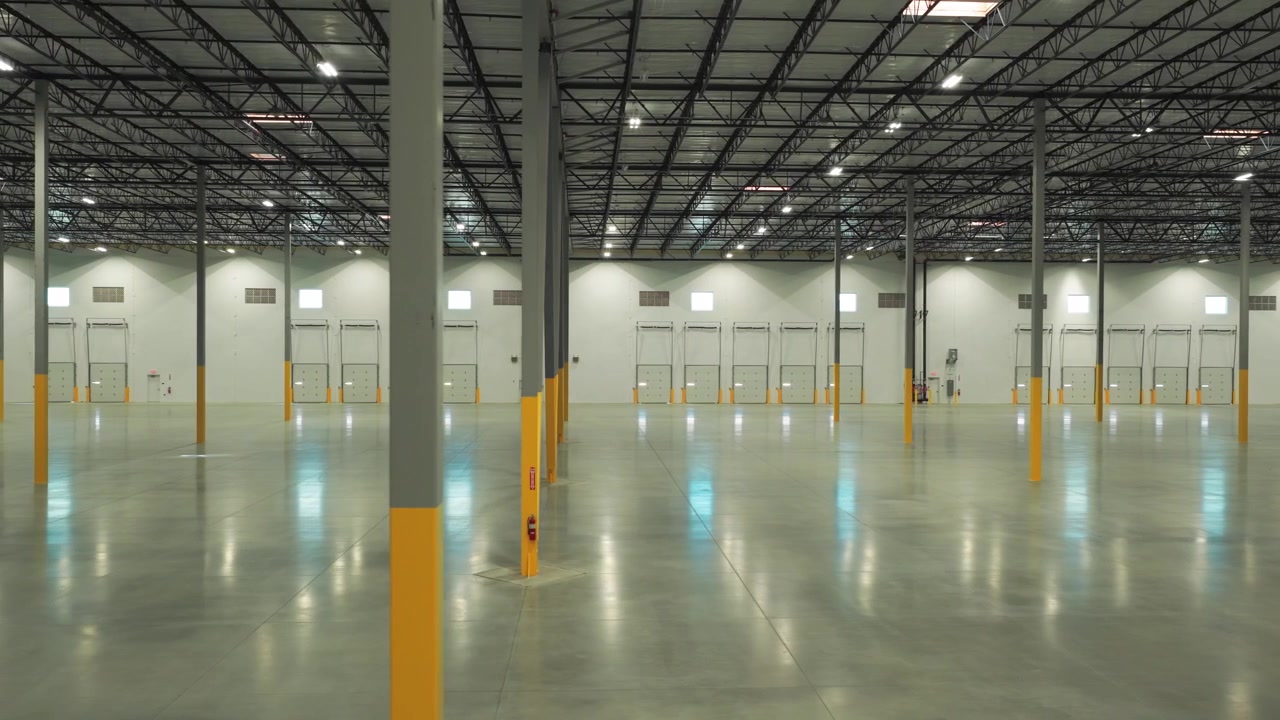Ampia carrellata aerea delle porte delle baie di carico per camion all'interno di un magazzino di distribuzione industriale. 4K