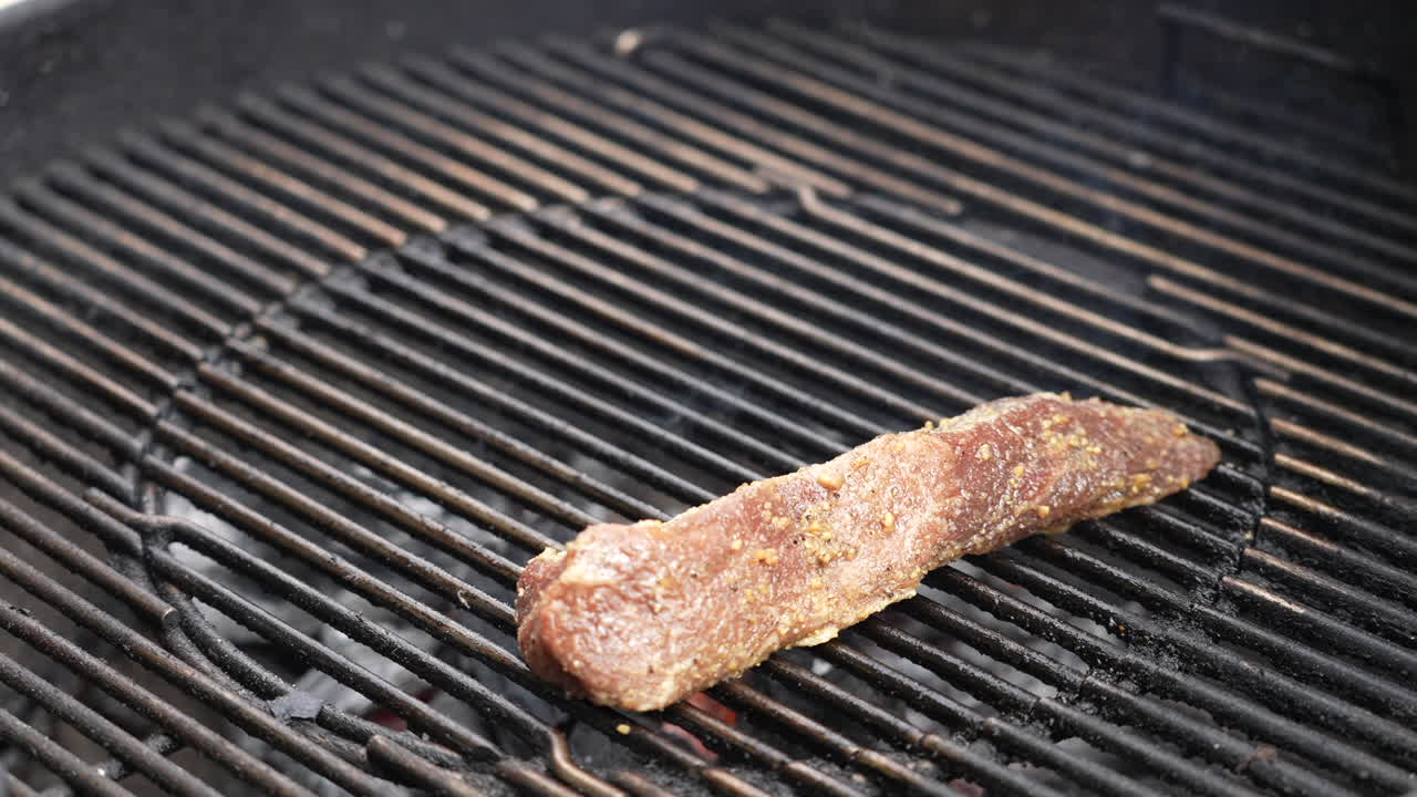 colocando cortes de carne de res marinados en la parrilla de carbón caliente del patio trasero - chisporroteando y fumando en cámara lenta
