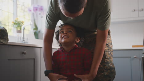 Madre-Del-Ejército-Americano-En-Casa-Uniforme-De-Licencia-Jugando-Con-Su-Hijo-En-La-Cocina-Familiar