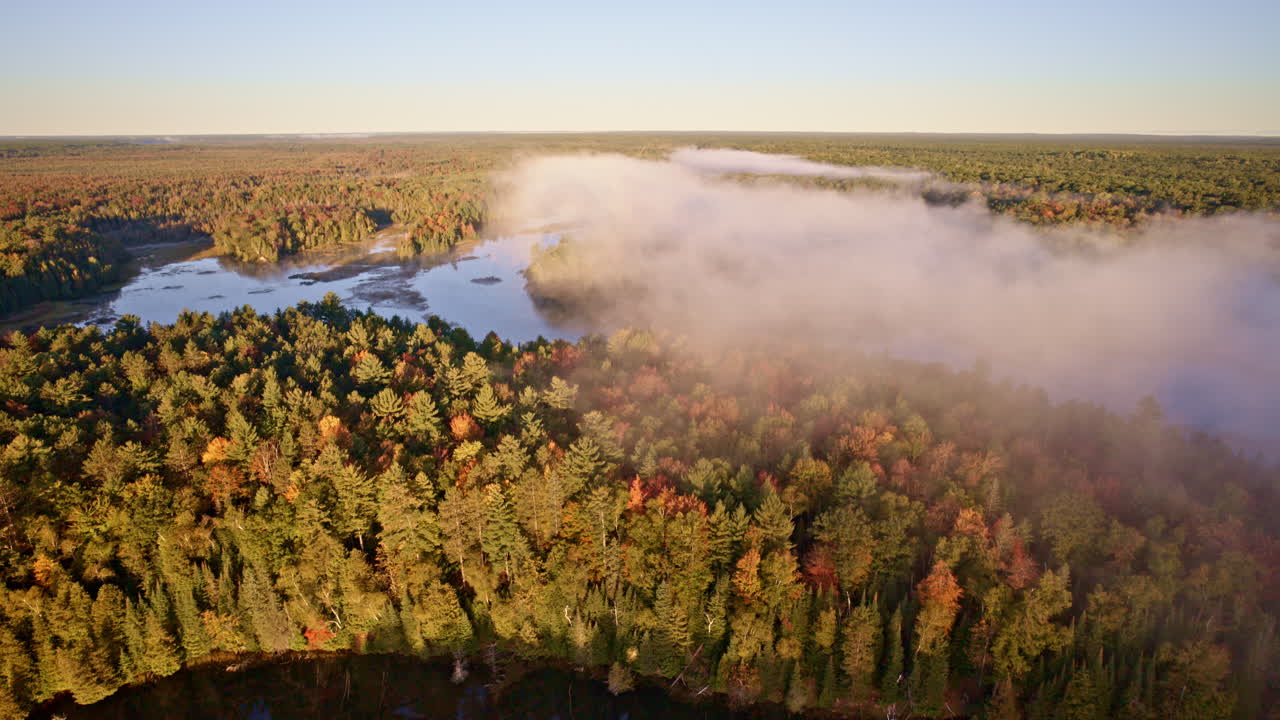 Drone footage of vapor curling above water at sunrise