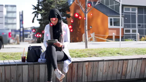 animación de una mujer biracial con hijab en la calle usando una tableta con un símbolo de corazón flotante