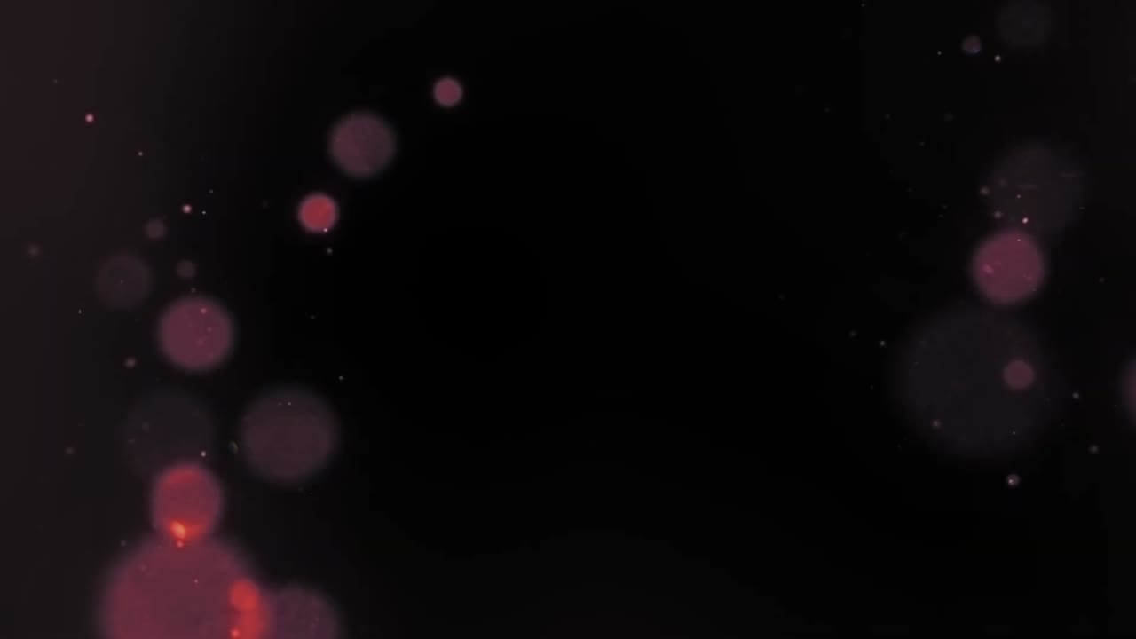 A soft, out-of-focus lens flare with vibrant, multi-colored bokeh particles drifts across a black background. For festive or magical scenes