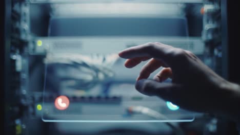 a close-up of a hand reaching towards a digital communication device surrounded by network cables inside a server rack, capturing a moment of technological interaction