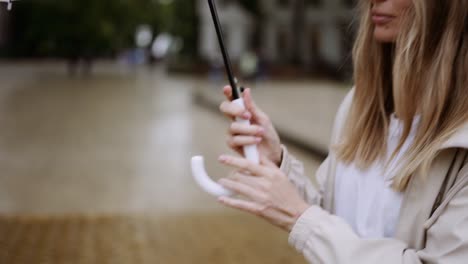 Blonde-woman-opens-transparent-umbrella-in-raining-day