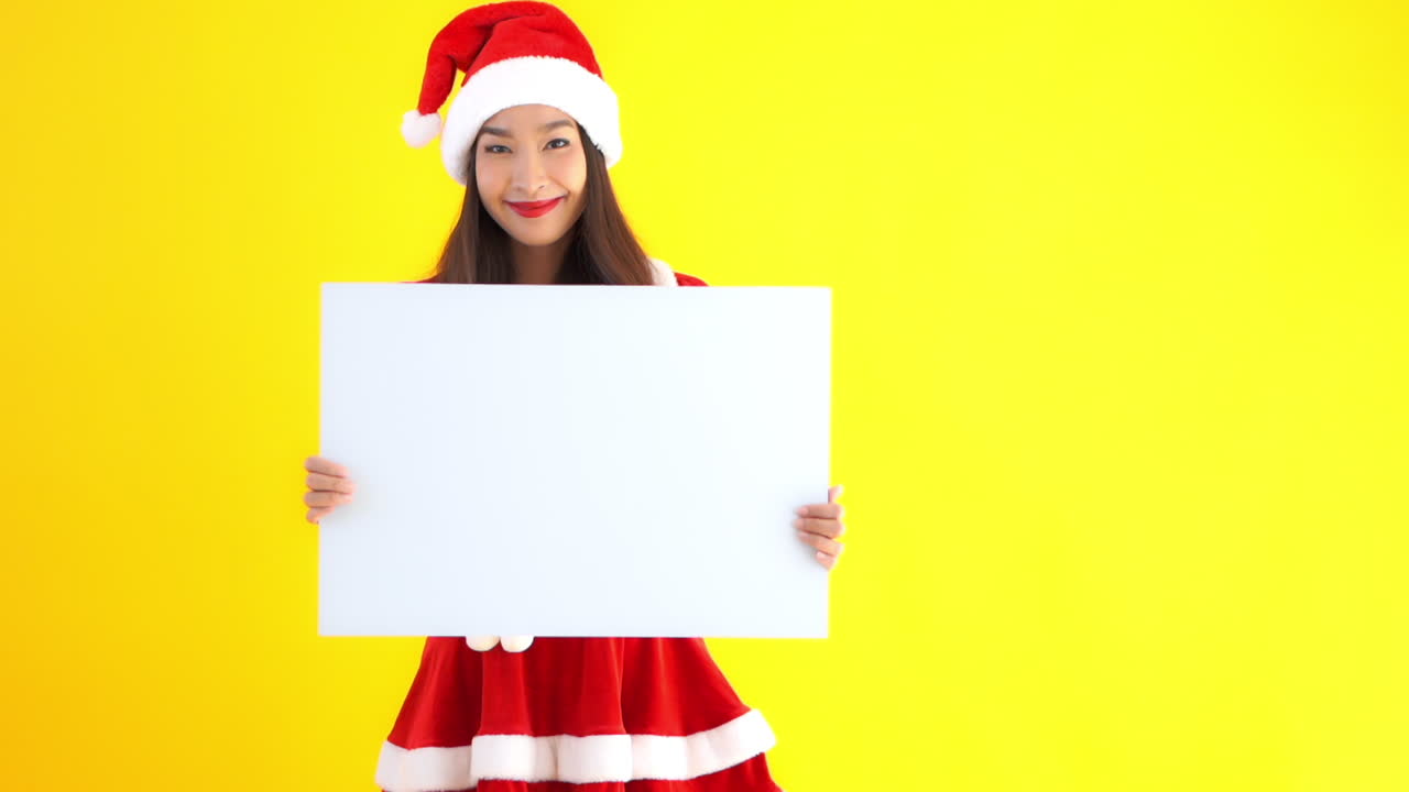 Template blank sign held by an attractive young Asian woman in a red and white Santa suit, Christmas.copy space