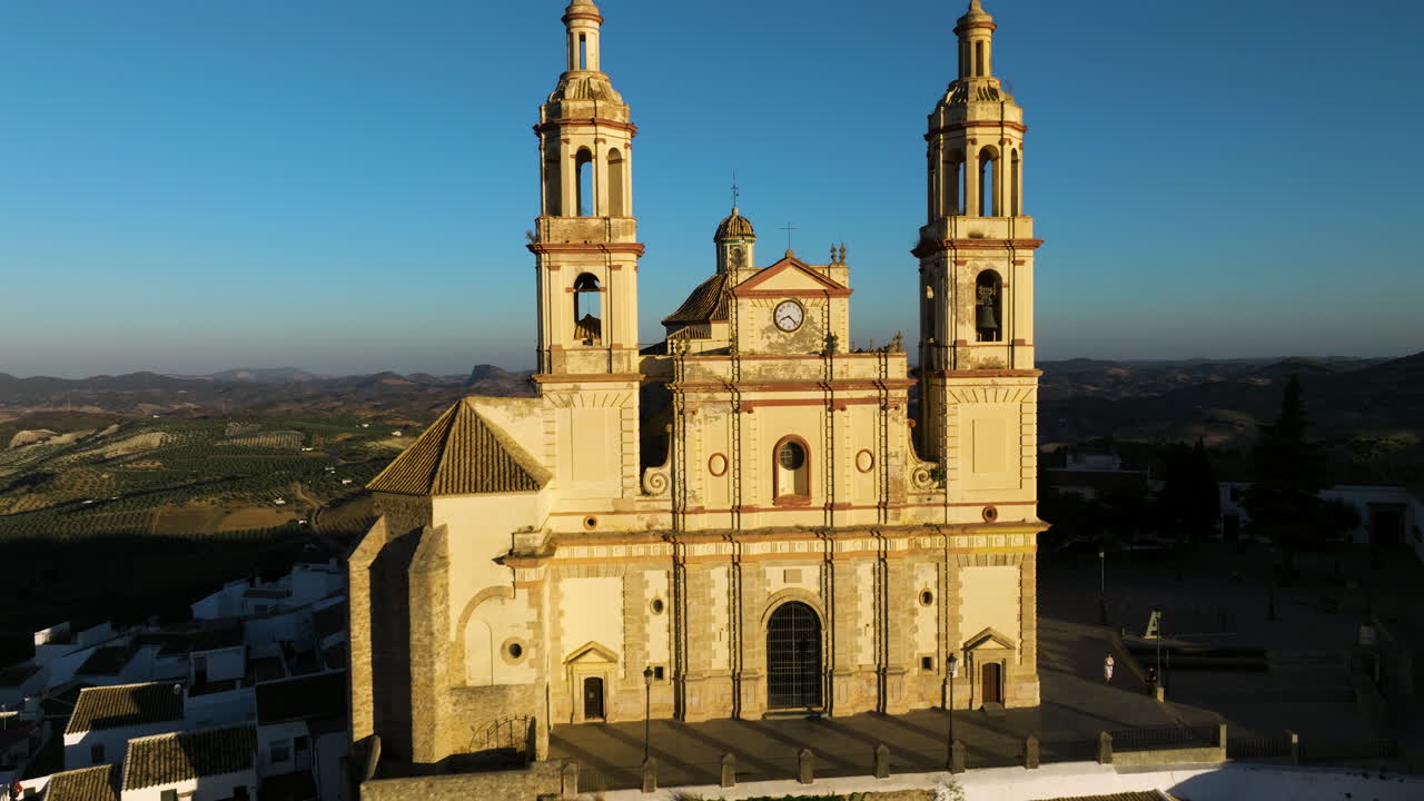 fachada iluminada por el sol de la iglesia de nuestra señora de la encarnación al amanecer en olvera, cádiz, españa