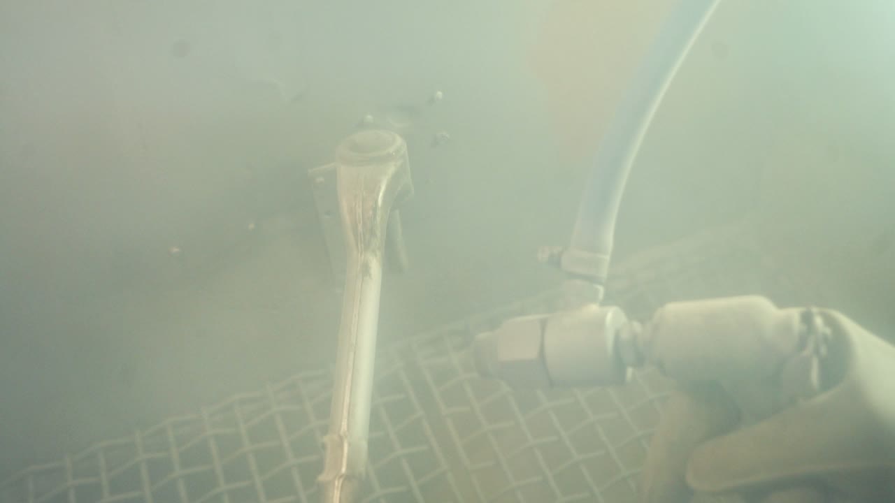 Hands of worker painting metal parts. Close up view of workman using spray gun for painting mechanical parts