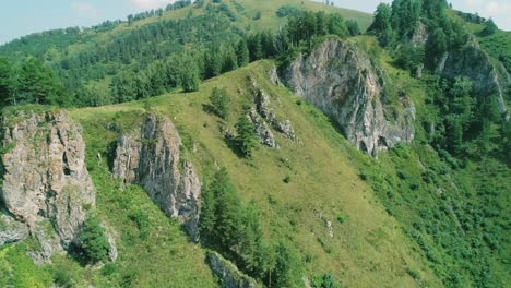 aerial view of green mountain with rocks formations and trees.