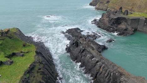 Aerial view over group of men standing on rocky coastline of Pembrokeshire Blue lagoon in Pembrokeshire Blue lagoon in Wales