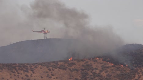 un helicóptero hace una gota de agua en un incendio forestal en las colinas del sur de california
